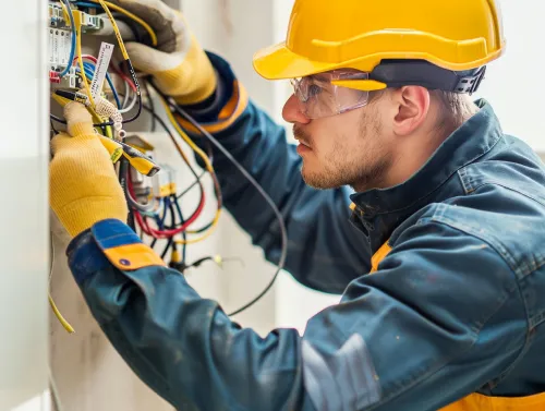 A professional electrician in Miami Beach repairing an electrical panel, carefully working with wires and components to ensure safe and efficient power distribution.